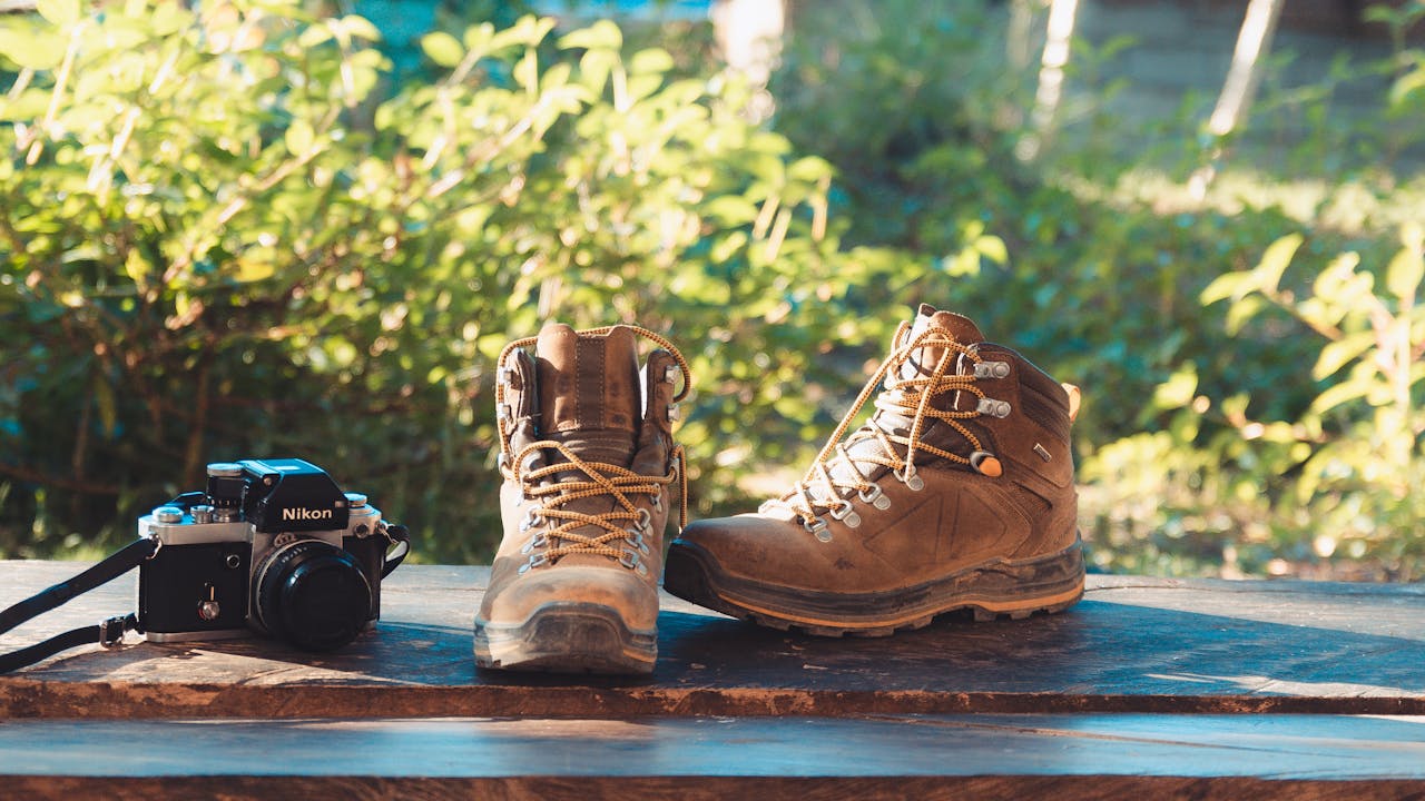 Outdoor hiking scene with boots and camera on a wooden surface, perfect for adventure themes.